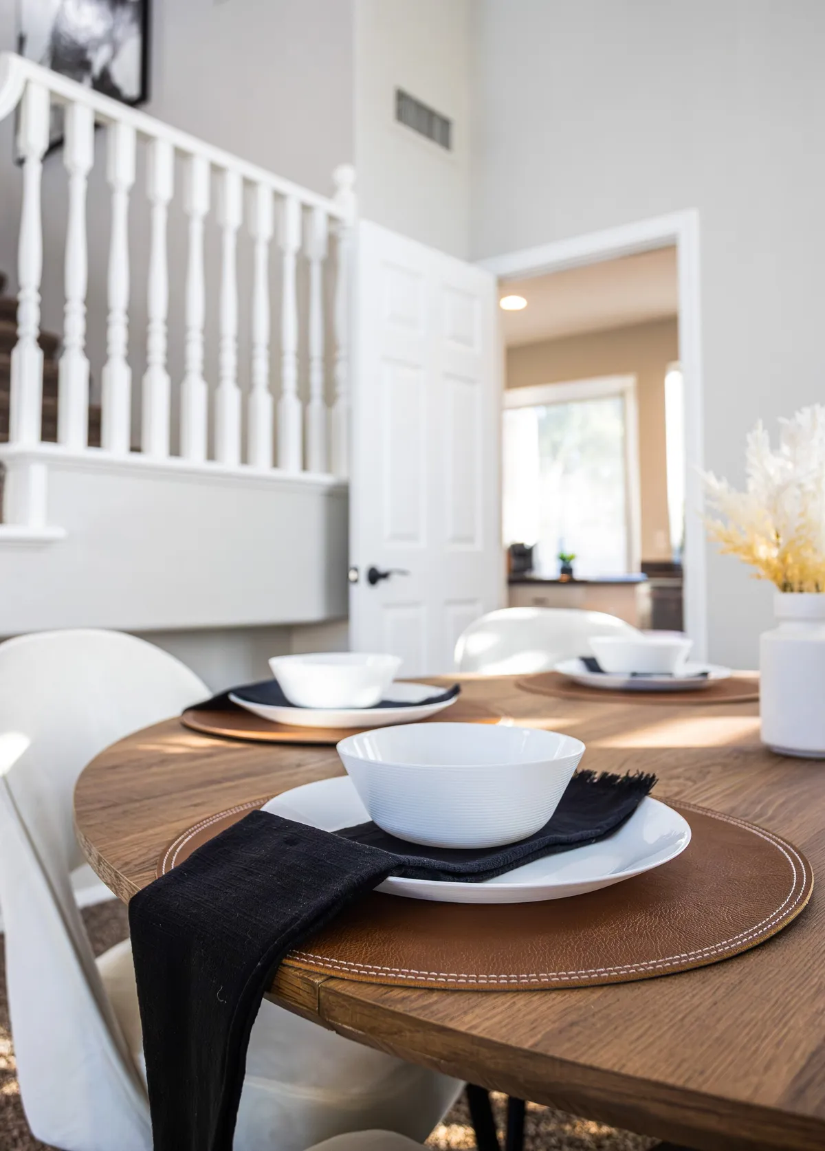 A cozy dining table set with ceramic bowls, a black napkin, and a decorative vase, situated in a warmly lit interior. The setting evokes a sense of intimacy and celebration, capturing the spirit of shared meals.